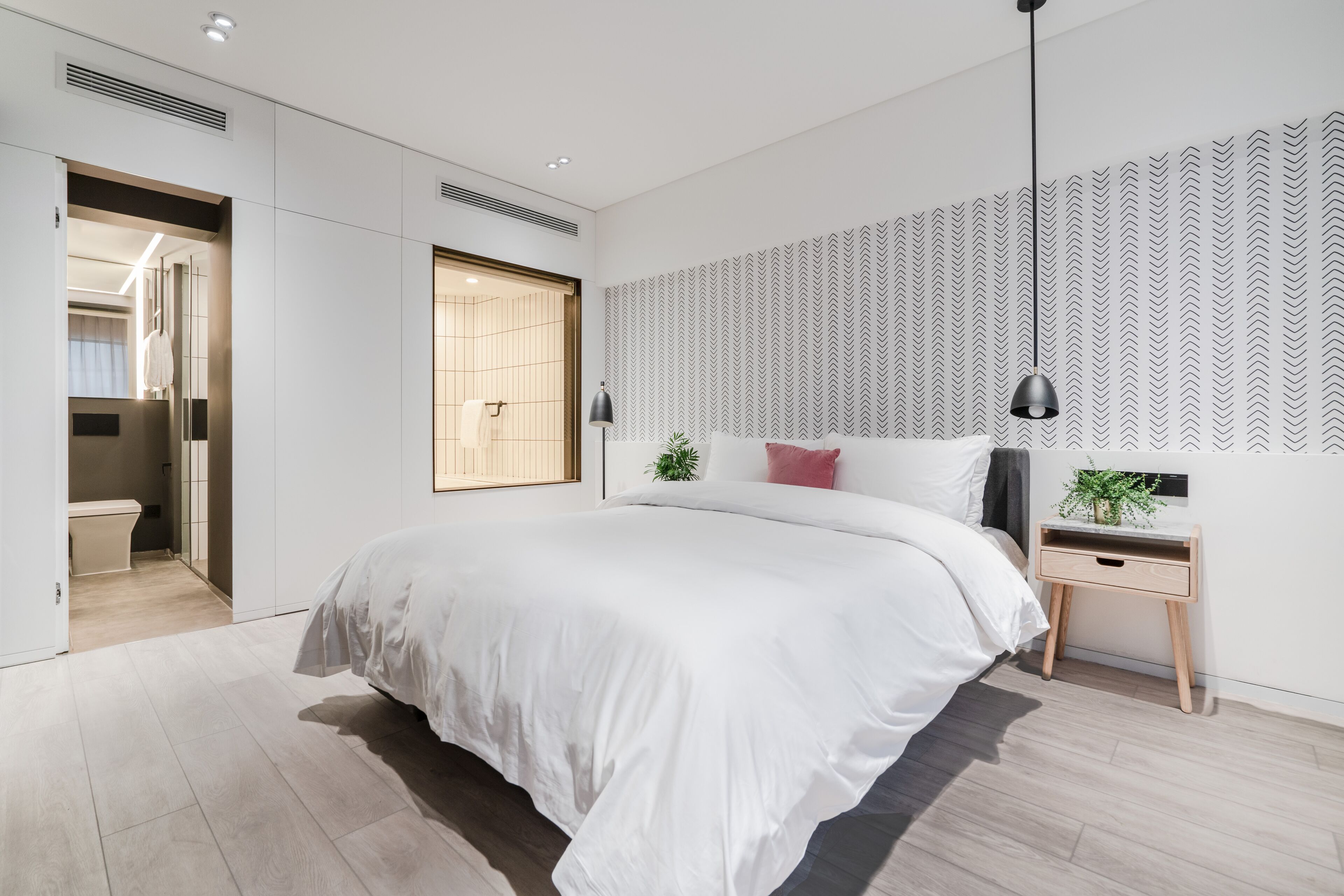 Un dormitorio moderno con una cama grande, mesitas de noche y una pared con diseño.