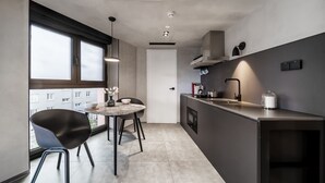 Une cuisine moderne avec un coin repas, de grandes fenêtres et une vue sur les bâtiments environnants.