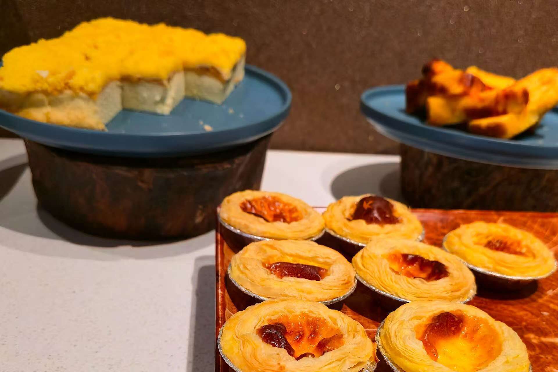 A tray of Portuguese custard tarts and a container of custard.
