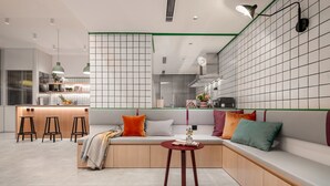 Une cuisine moderne dotée d’un îlot central intégré, de tabourets de bar et d’un coin salon avec des coussins.