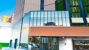 Un grand hôtel au design moderne, caractérisé par une bande verticale de fenêtres bien visible et un vaste hall d’entrée doté de portes en verre.