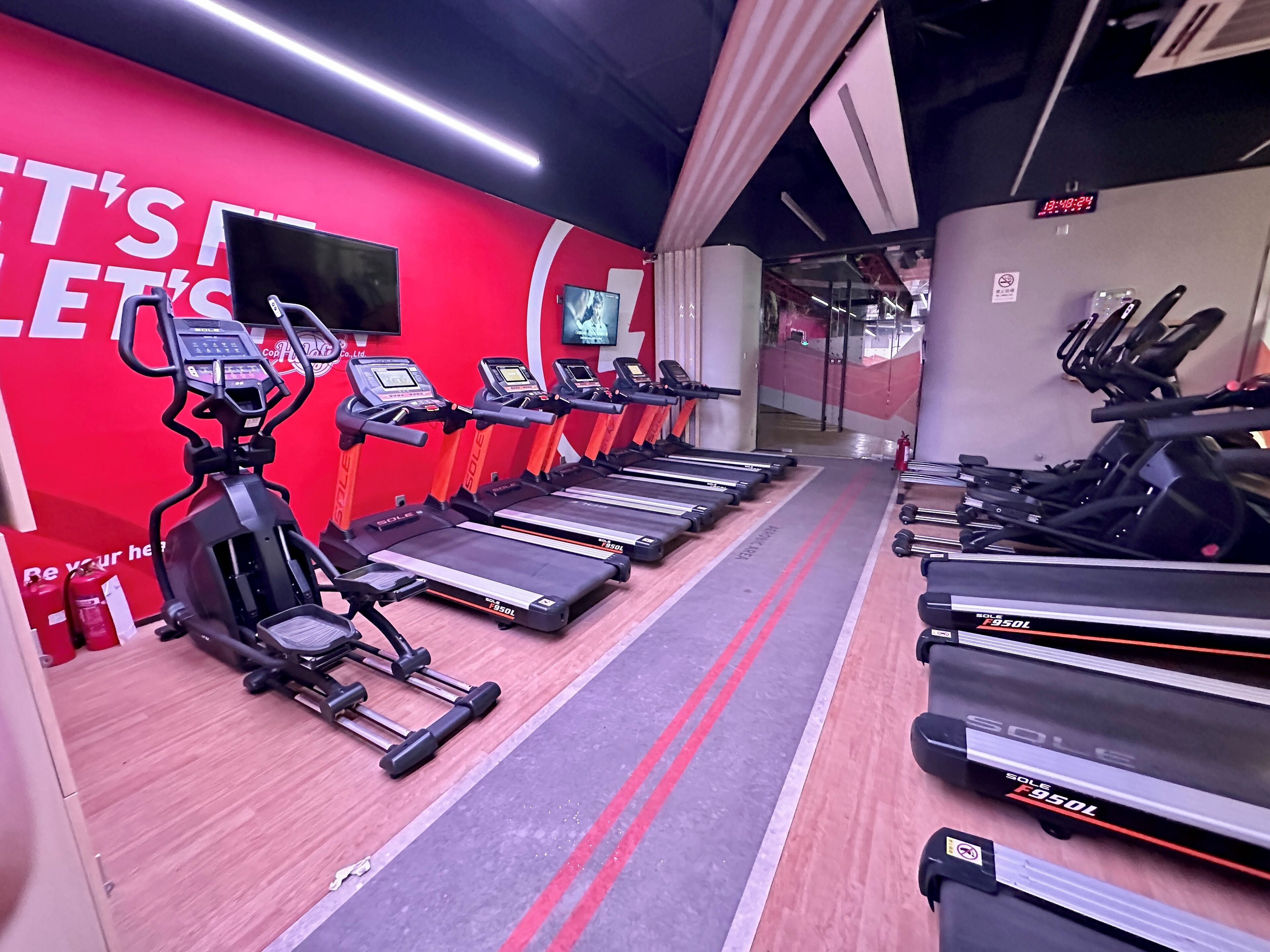 Un gimnasio con cintas de correr, elípticas y máquinas de pesas.