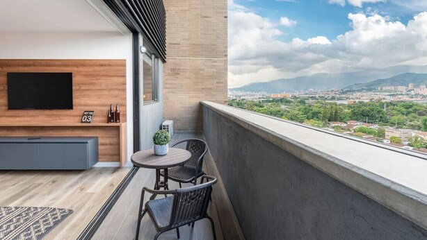A balcony with a TV, seating, and a table with chairs. - Go Living 708 · Luxury Apt-balcony and city view-AC and coworking (Medellín)