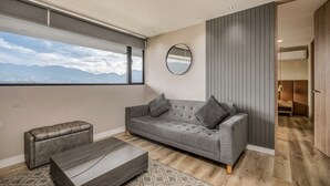 Un salon moderne avec un canapé gris, un miroir rond et une table basse en bois.