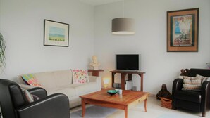 Una sala de estar con un sofá, una mesa de centro, un televisor, una lámpara y un cuadro en la pared.