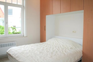 Une chambre à coucher avec un lit, une fenêtre et un lambris en bois sur le mur.