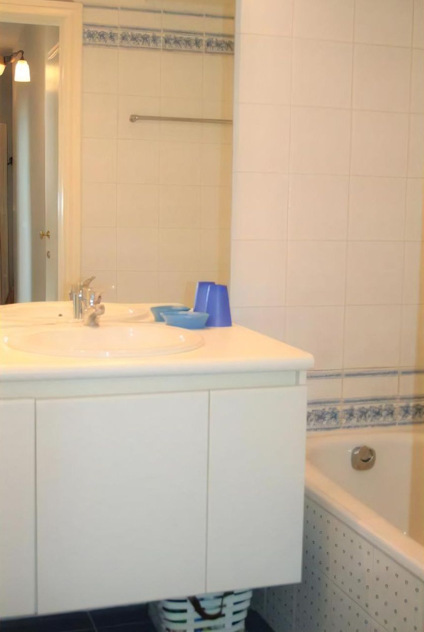 Un bagno con un lavandino bianco, uno specchio e una vasca.