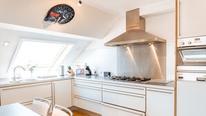 Una cocina moderna con armarios blancos, una campana extractora de acero inoxidable y un horno empotrado.