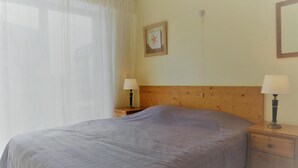 Une chambre à coucher comprenant un lit, deux tables de chevet, une commode, une tête de lit en bois, une décoration murale en forme d’étoile et un miroir.