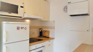 Une cuisine équipée d’un four à micro-ondes, d’un réfrigérateur, d’une cuisinière et d’un plan de travail en bois.
