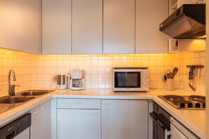 A modern kitchen with white cabinets, a built-in dishwasher, a microwave, and a stove. - Charlotte B2 - 1-bedroom apartment 150m from the sea (De Haan)