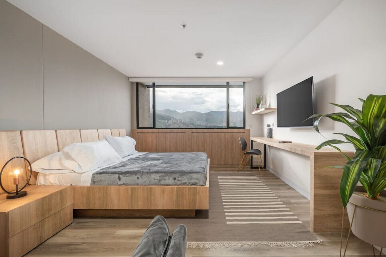 A modern bedroom with a bed, bedside table, and a desk area.