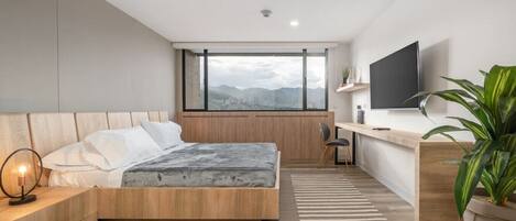A modern bedroom with a bed, bedside table, and a desk area.