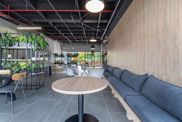 Een modern café met een ronde tafel, zitgedeelte en planten.