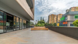 Een modern gebouw met een ruime buitenruimte, compleet met een houten bank en een glazen gevel.