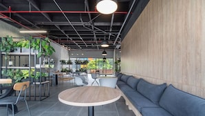 Un café moderno con una mesa redonda, zona de estar y plantas.