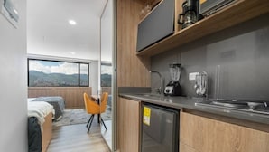 A compact kitchen with a refrigerator, coffee maker, and blender. - Modern Studio Loft El Poblado-Gym, Coworking (Medellín)