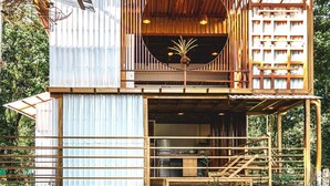Una estructura de madera de dos pisos con un balcón y un área de cocina visible.