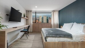 Une chambre à coucher moderne avec un lit, un bureau et un téléviseur.