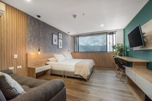 Un dormitorio moderno con cama, escritorio y televisor.