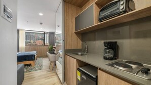 Une cuisine de taille réduite équipée d’une machine à café, d’un évier et d’un réfrigérateur compact.