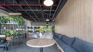 Un café moderne avec une table ronde, un espace salon et des plantes.
