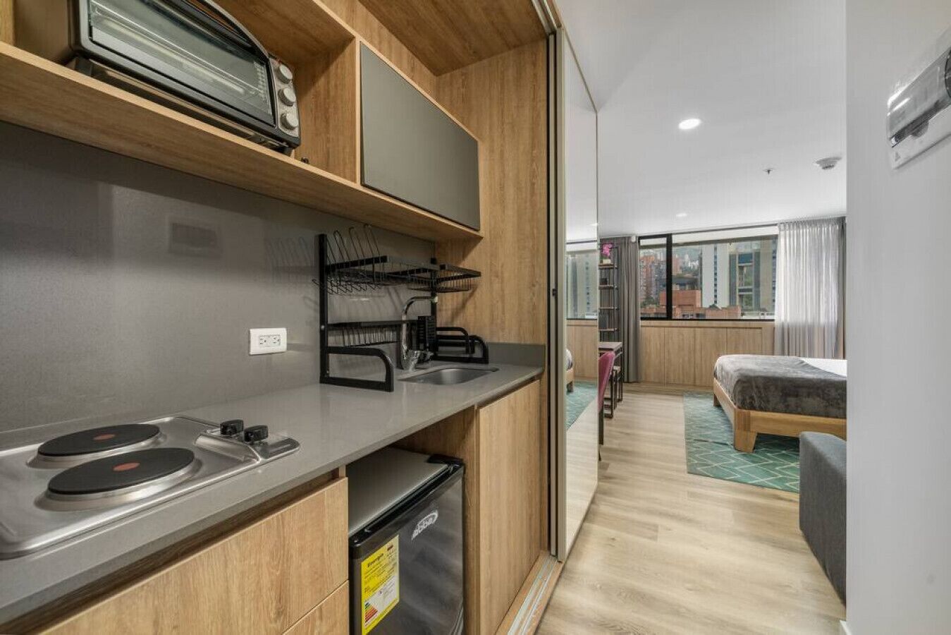 A compact kitchenette with a stove, sink, and a small refrigerator.
