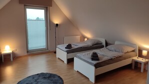 A bedroom with two beds, a large window, and a floor lamp.