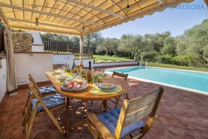 Un área de comedor al aire libre con piscina y pared de piedra.