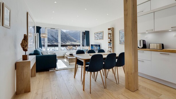 Een moderne woonkamer met een eetgedeelte, grote ramen en uitzicht op bergen.