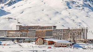 Een hotel met meerdere verdiepingen, skipistes en een bergachtig landschap.