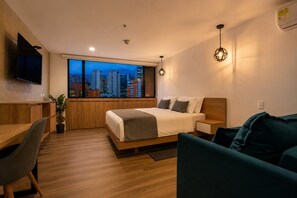Une chambre d’hôtel moderne avec vue sur la ville, comprenant un lit, un bureau et un canapé.