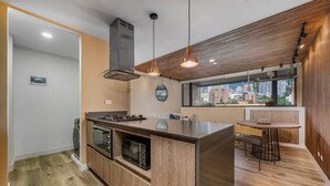 Una cocina moderna con una isla central, horno empotrado y microondas. Hay un comedor con una mesa redonda y sillas.