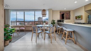 Una cocina moderna con un ventanal grande, un comedor con sillas y una barra.