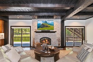 Una sala de estar con chimenea, un televisor de pantalla plana grande montado encima y un juego de sofá.