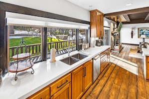 Una cocina con un ventanal grande, armarios de madera y vistas a un paisaje nevado.
