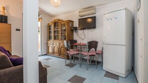 A compact kitchen with a dining table, chairs, a refrigerator, a TV, and a wooden cabinet. - Apartments Horvatic (Vir)