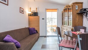 A living room with a brown sofa, purple cushions, a wooden cabinet, and a dining table with chairs. - Apartments Horvatic (Vir)