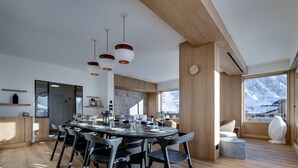 Zona pranzo moderna con tavolo rotondo, sedie nere e pavimento in legno.