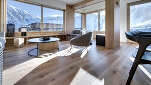 Una camera moderna con ampie finestre, pavimento in legno e vista sulle montagne innevate.