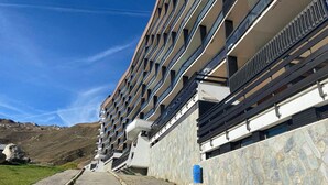 Un hotel moderno con diversi balconi, facciata in pietra e una vista aperta sul paesaggio circostante.