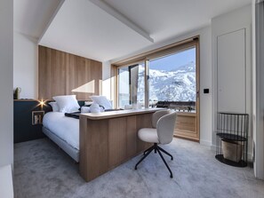 A modern hotel room with a bed, a desk, and a view of a snowy mountain. - Spacious renovated apartment with terrace and parking in Tignes (Tignes)