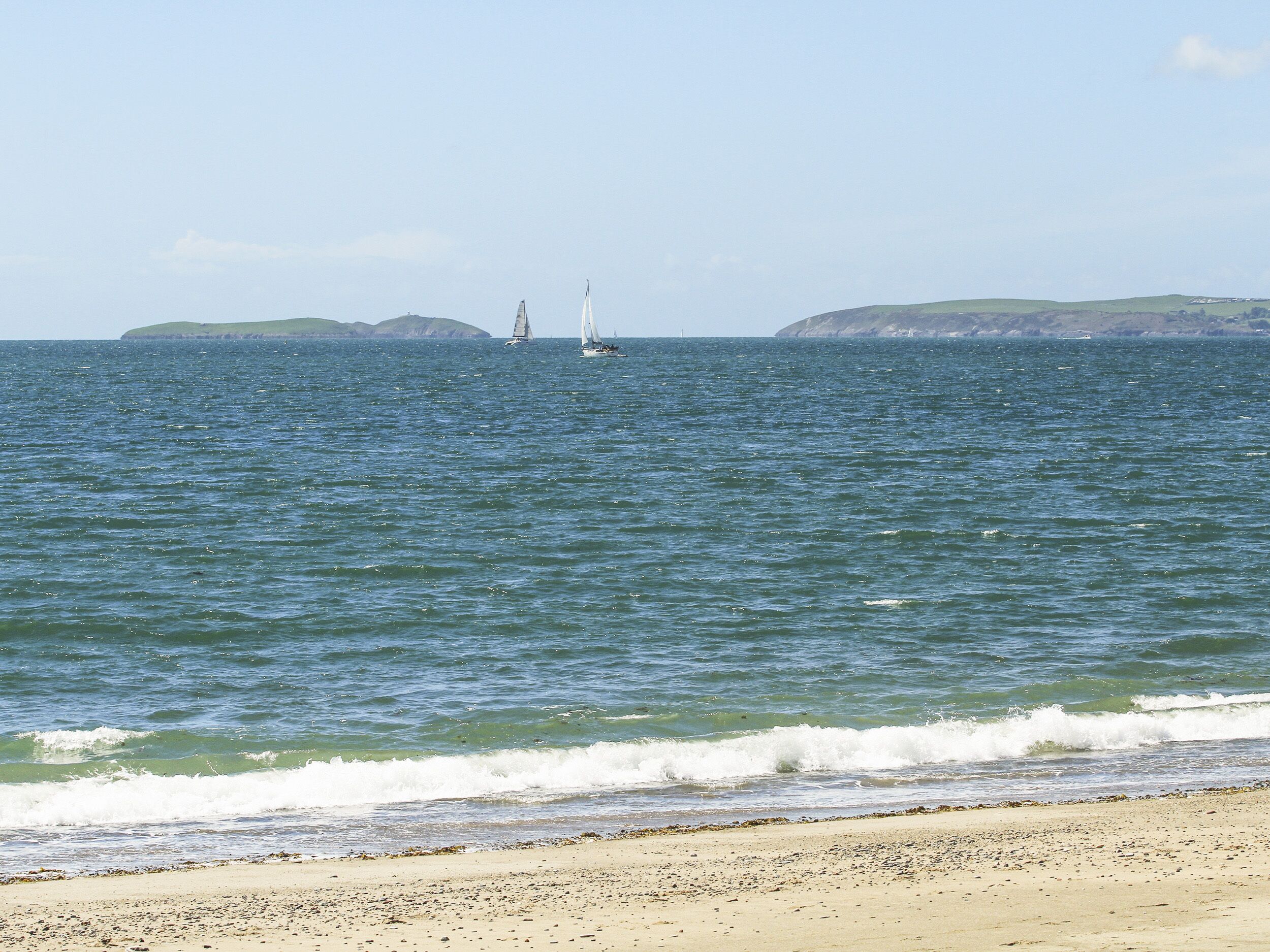 A beach with a sandy shore and calm sea.