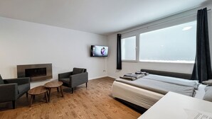 A modern hotel room with a flat-screen TV, a sofa, a small table, and a bed. - Classy Studio in Saas-fee, Alps, Switzerland (Saas-Fee)