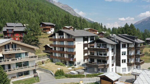 A cluster of multi-story buildings with balconies, surrounded by forested mountains. - Classy Studio in Saas-fee, Alps, Switzerland (Saas-Fee)