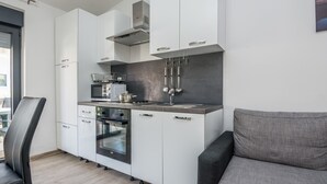 Una cocina moderna con armarios blancos, horno empotrado y estufa a gas.