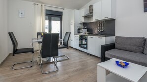 Un espacio habitable compacto con kitchenette, comedor y zona de estar.