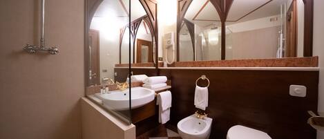 A bathroom with a shower, sink, bidet, and toilet.