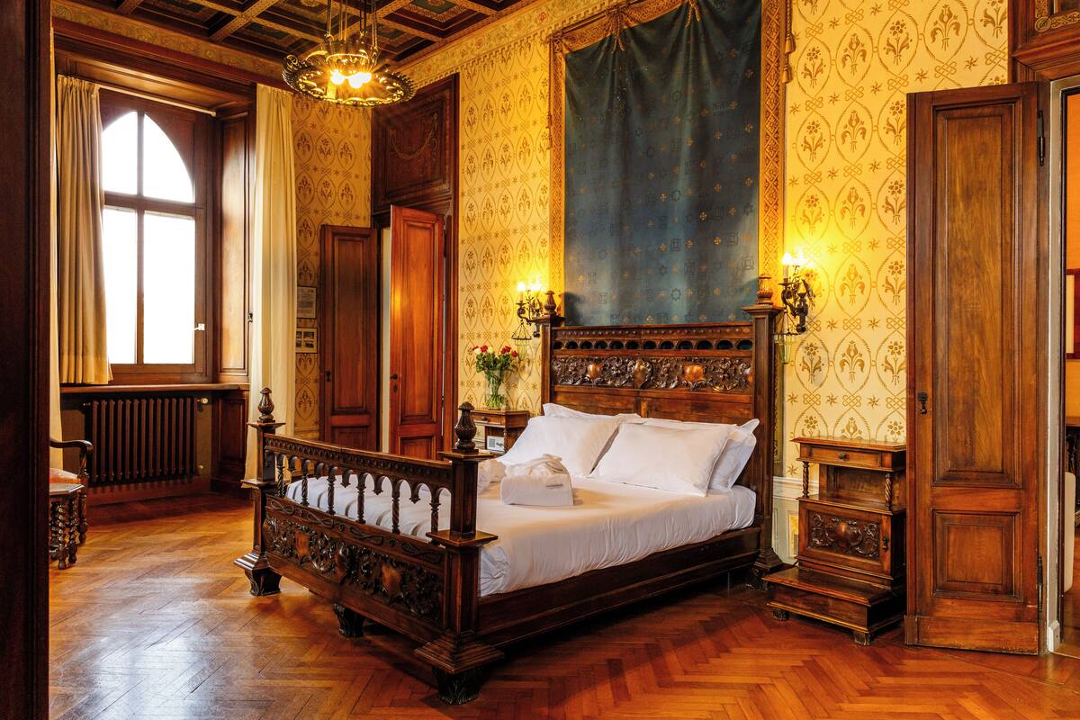 Ein traditionell eingerichtetes Schlafzimmer mit Himmelbett, Holzböden und aufwendigen Wandverzierungen.