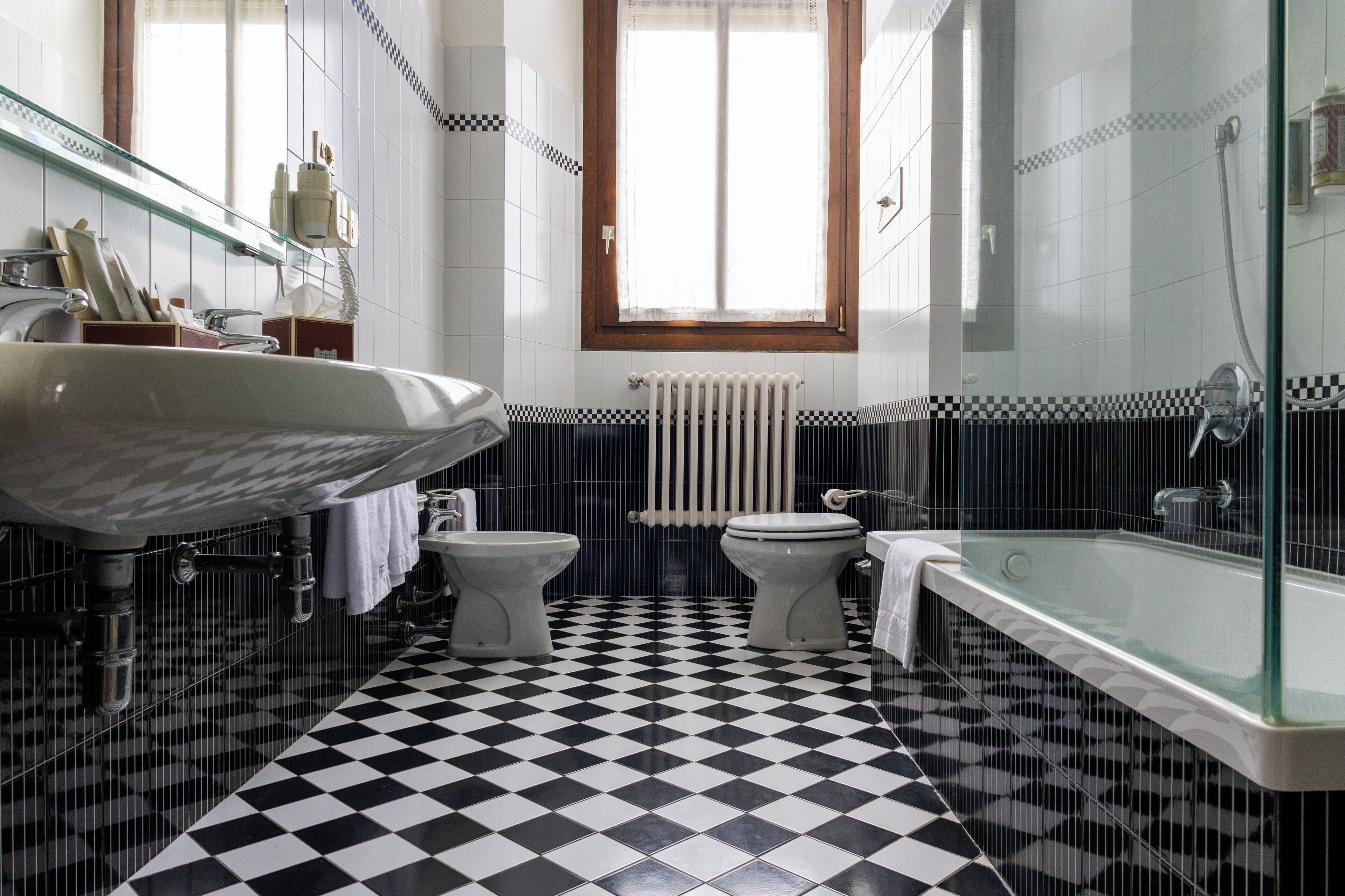 Ein Badezimmer mit Schachbrettboden, einem großen Waschbecken, einer Toilette und einer Badewanne.